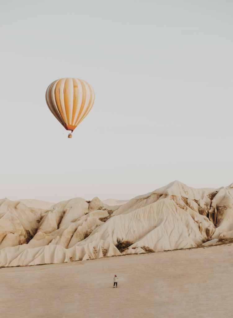 person standing on desert front of hot air balloon